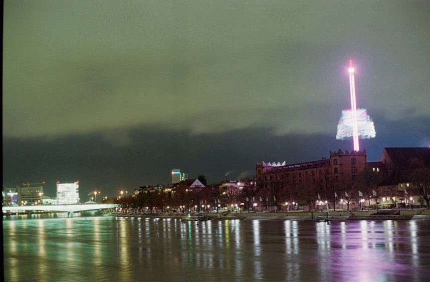 Basel. Blick von der Mittleren Brücke auf die Kaserne. Langzeitbelichtung eines Herbstmesse-Fahrgeschäfts.